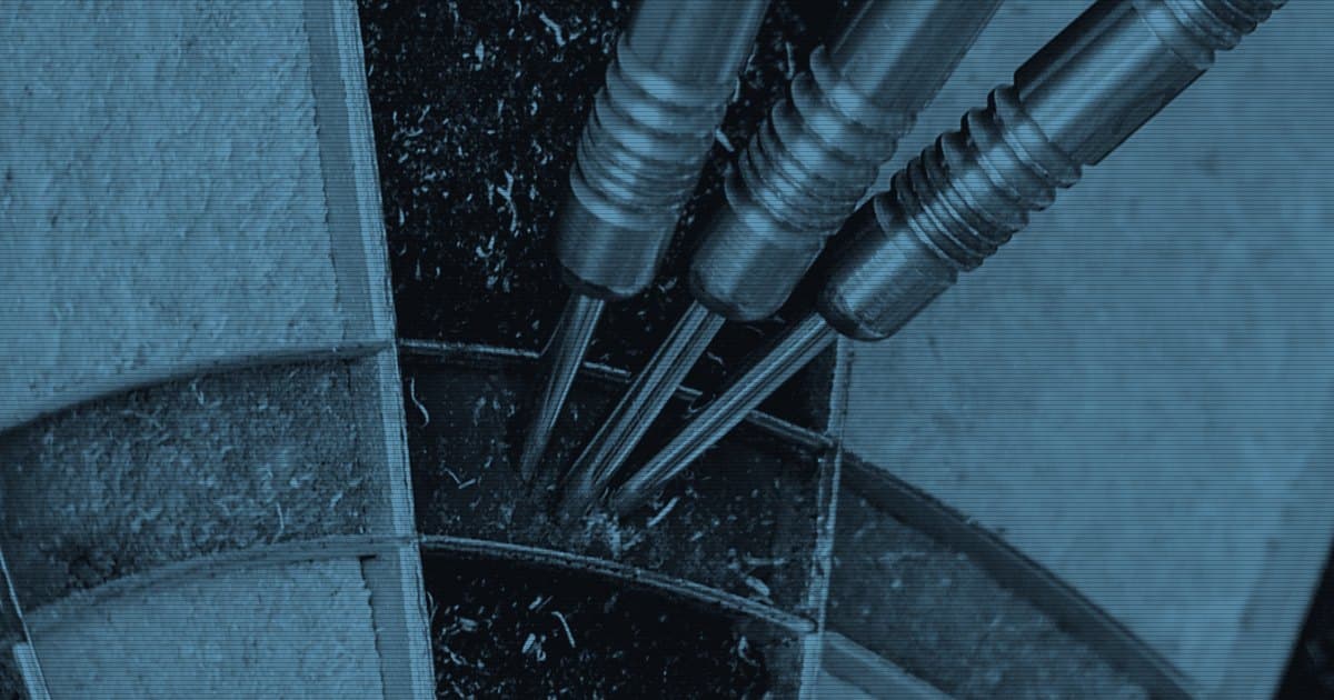 Три дротика воткнуты в сектор мишени для дартса, снято вплотную