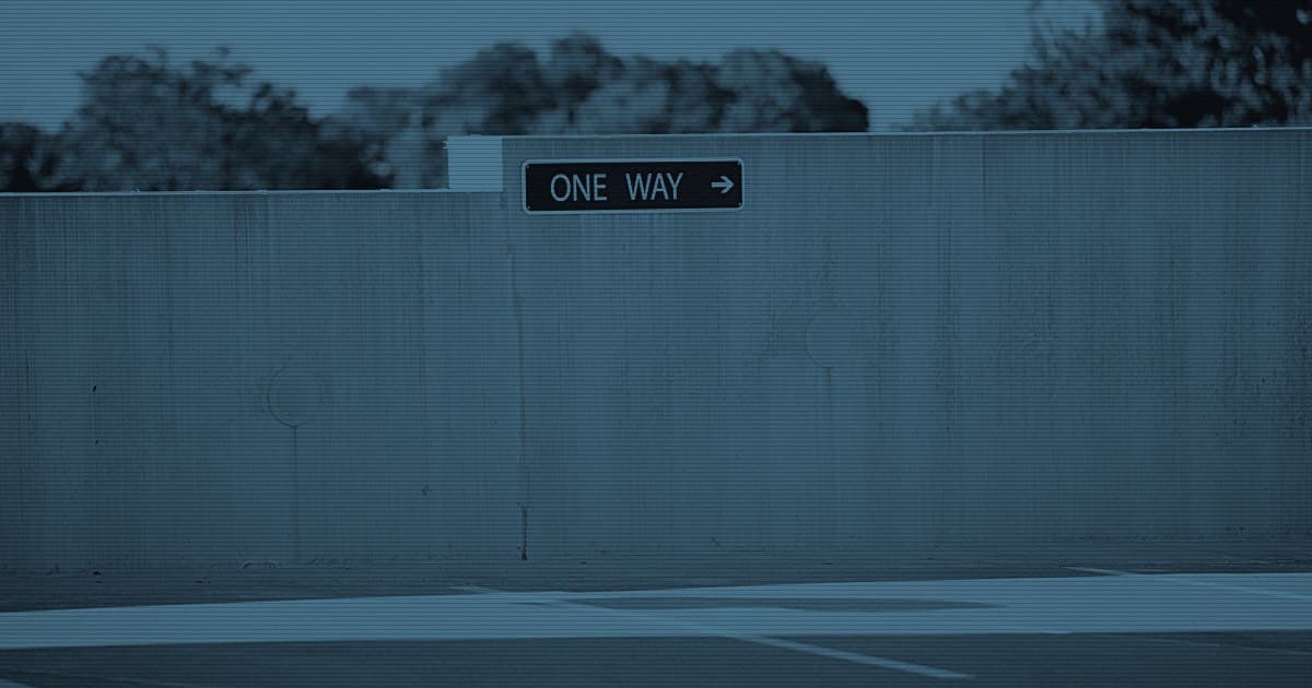 Табличка One way со стрелкой на бетонной стене парковки